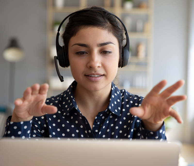 A photograph of a young woman wearing a headset have a conversation online