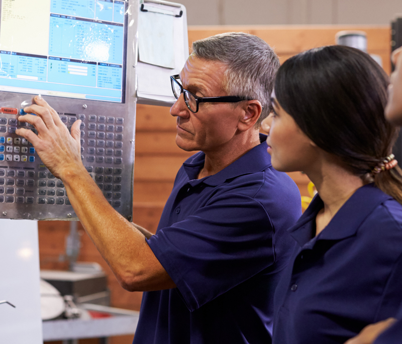 A photograph of an employee showing a trainee how to operate machinery